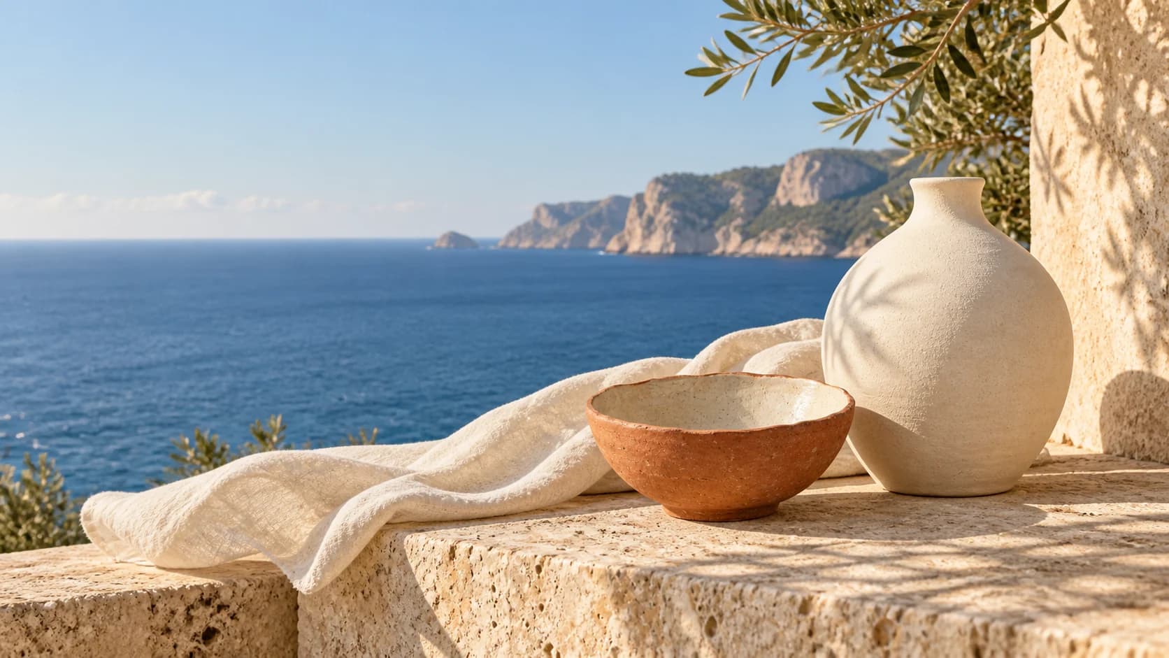 Jarrón y cuenco sobre una terraza de piedra frente al Mediterráneo